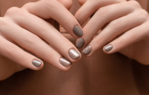 female-hands-with-brown-nail-design-brown-fabric-surface
